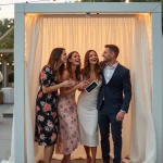 Groupe d'invités joyeux posant dans un photobooth élégant lors d'une réception de mariage en plein air